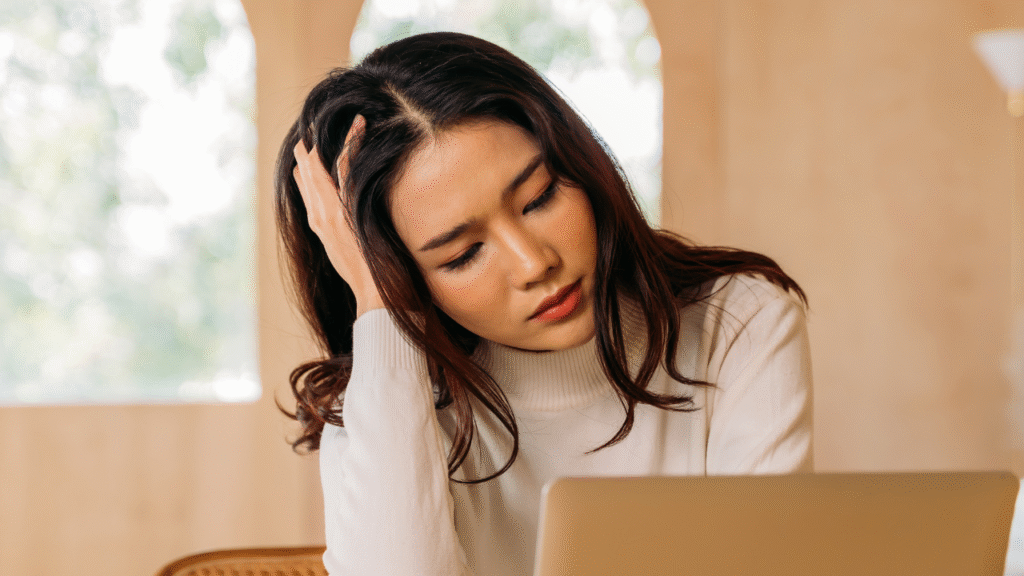 10 Common Mistakes That Make New Transaction Coordinators Look Unprofessional 1 woman in front of a computer resting her head in her hand, worrying about the most common TC mistakes
