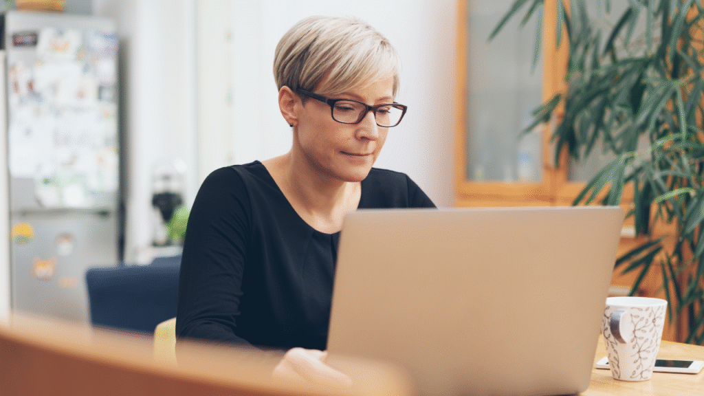 How to Handle Agents Who Want Just a Little Help (Without Burning Out as a TC) 1 Transaction coordinator working on a laptop in a home office with a coffee mug nearby.