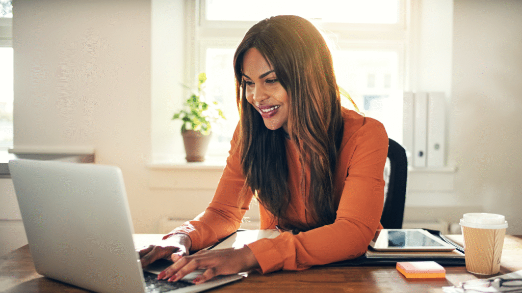 Should You Offer Listing Coordination as a Transaction Coordinator? 1 Professional woman working on a laptop in a bright office, representing listing coordination and transaction coordination services in real estate.