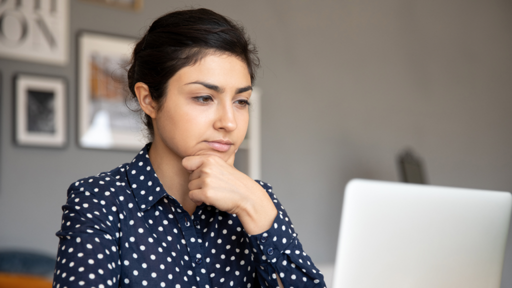 Transaction Coordinator Red Flags to Avoid 1 Woman working on a laptop with a thoughtful expression, representing Transaction Coordinator red flags to avoid
