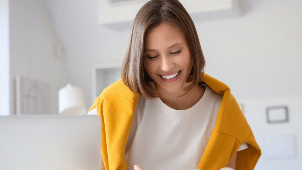 Want to Know How to Get Clients for Transaction Coordinators? Start by Investing in Your Business the Right Way 1 Young woman working from home on a laptop while reviewing notes and building her business as a Transaction Coordinator.